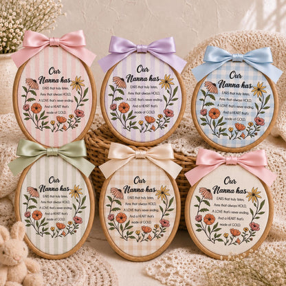 May include: Six oval wooden embroidery hoops featuring fabric with floral illustrations and the text: Our Nanna has EARS that truly listen, Arms that always HOLD, A LOVE that's never ending, And a HEART that's made of GOLD. Each hoop has a satin bow.