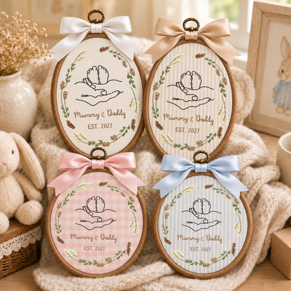 May include: Four oval wooden embroidery hoops featuring fabric backgrounds with baby feet held in hands, floral wreaths, and the text Mummy &amp; Daddy EST. 2027. Each hoop is topped with a satin bow in white, beige, pink, or light blue.