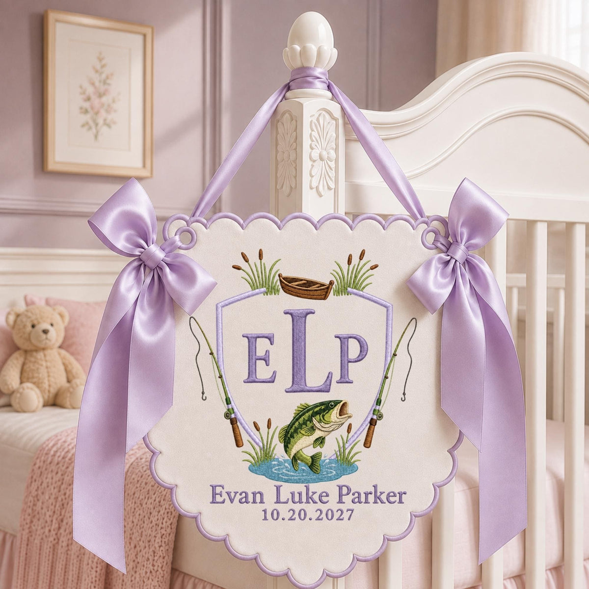 May include: A cream-colored scalloped wall hanging featuring an embroidered shield with the letters ELP, a small boat, two fishing rods, and a green fish. The name Evan Luke Parker and the date 10.20.2027 are stitched below, accented by lavender satin bows.