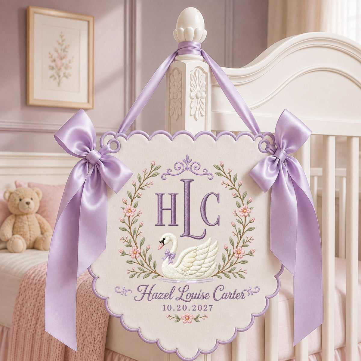 May include: A scalloped, off-white fabric wall hanging featuring an embroidered swan, floral wreath, and the monogram HLC. The text reads Hazel Louise Carter and 10.20.2027. It is adorned with two large, light purple satin bows and matching ribbon.