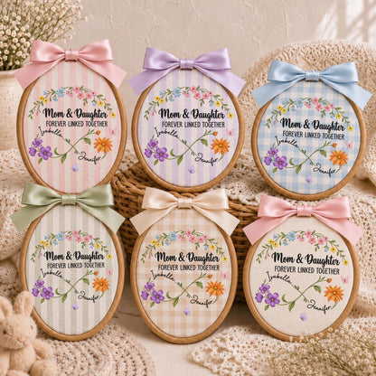 May include: Six oval embroidery hoops featuring fabric with various patterns and colors. Each hoop displays a floral wreath, an infinity symbol, and the text 'Mom &amp; Daughter FOREVER LINKED TOGETHER' with the names 'Isabella' and 'Jennifer' printed on them.