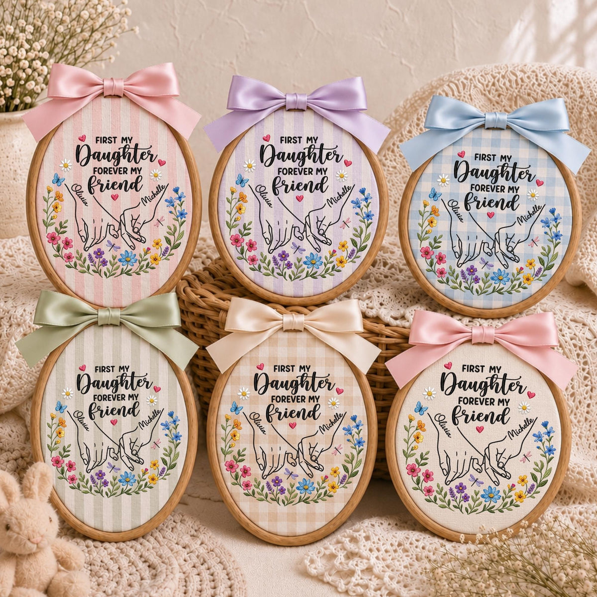 May include: Six oval wooden embroidery hoops featuring fabric with various patterns and colors. Each hoop displays a printed illustration of two hands pinky-promising, surrounded by colorful flowers and the text First My Daughter Forever My Friend.