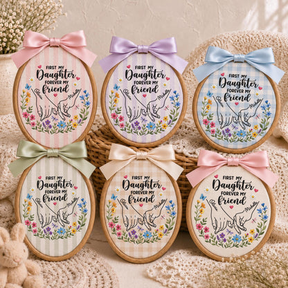 May include: Six oval wooden embroidery hoops featuring fabric with various patterns and colors. Each hoop displays a printed illustration of two hands pinky-promising, surrounded by colorful flowers and the text First My Daughter Forever My Friend.