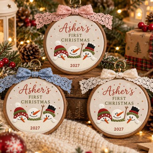 May include: Three circular wooden embroidery hoops featuring fabric with embroidered snowmen wearing colorful hats. The text reads Asher's FIRST CHRISTMAS 2027. Each hoop is topped with a decorative lace bow in pink, blue, or cream.