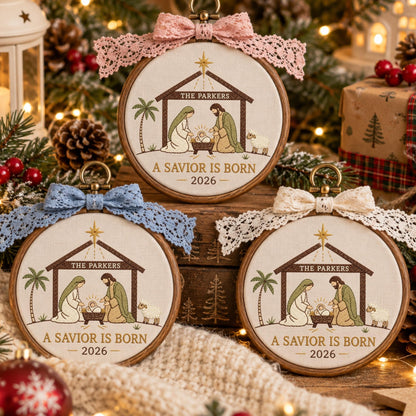 May include: Three circular wooden embroidery hoops featuring a nativity scene with a manger, palm tree, and sheep. The text reads THE PARKERS, A SAVIOR IS BORN, and 2026. Each hoop is topped with a decorative lace bow in pink, blue, or white.